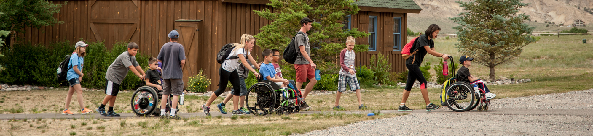 Volunteers pushing campers who are in wheelchairs at Roundup River Ranch