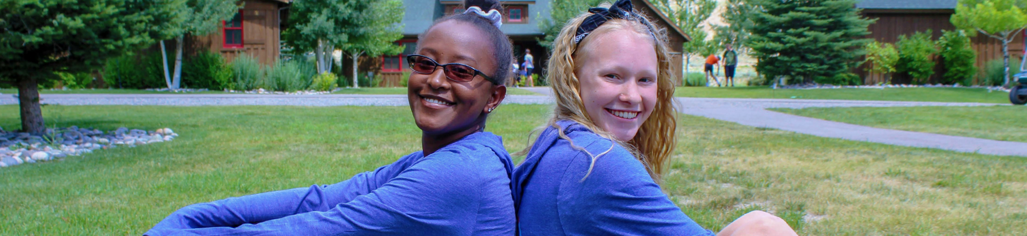 two campers sitting and smiling back to back