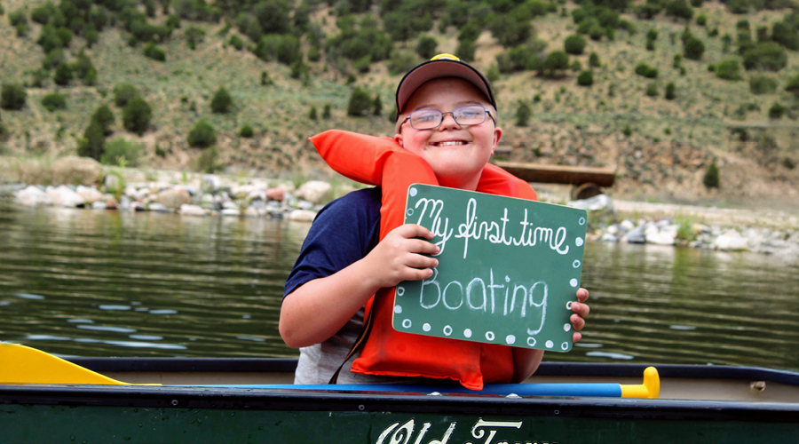 Camper in canoe with sign that says "first day boating"