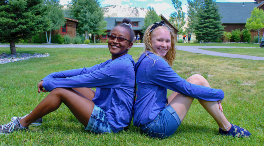 two campers sitting and smiling back to back
