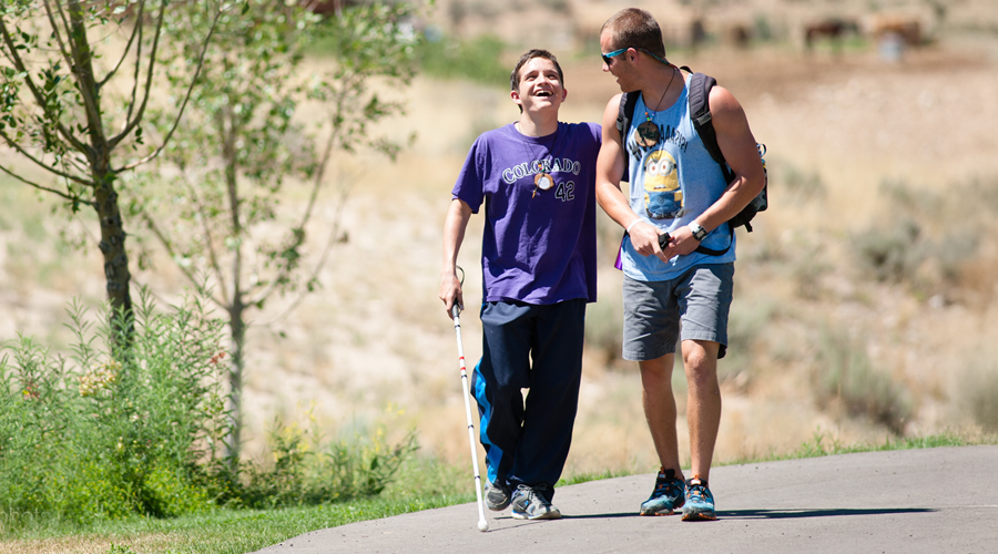 blind camper and camp counselor walking and laughing.