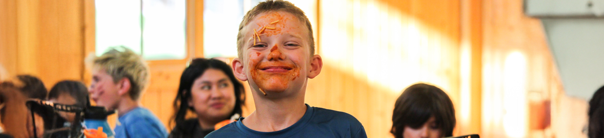 camper with spaghetti all over his face smiling