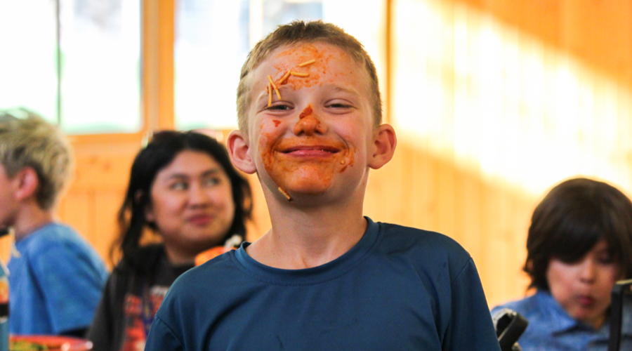 camper with spaghetti all over his face smiling
